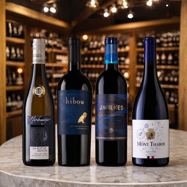 Four wine bottles on a table with a wine cellar background