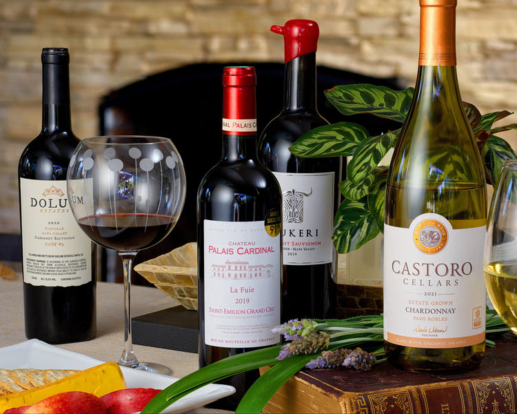 Collection of wine bottles and glasses on a wooden table with a blurred background