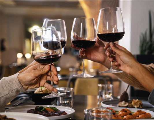 Four people having a cheers over dinner with red wine