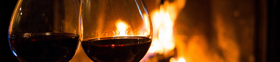 Pair of red wine in a glass with fireplace background