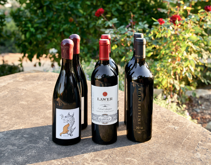 Six bottles of wine in 3 rows displayed outside by a rose bush