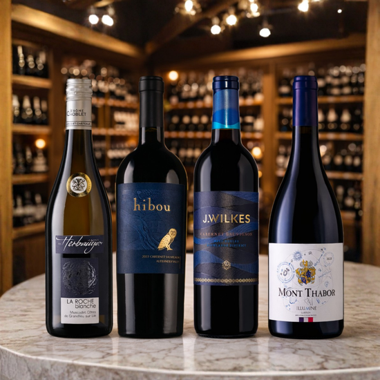 Four wine bottles on a table with a wine cellar background