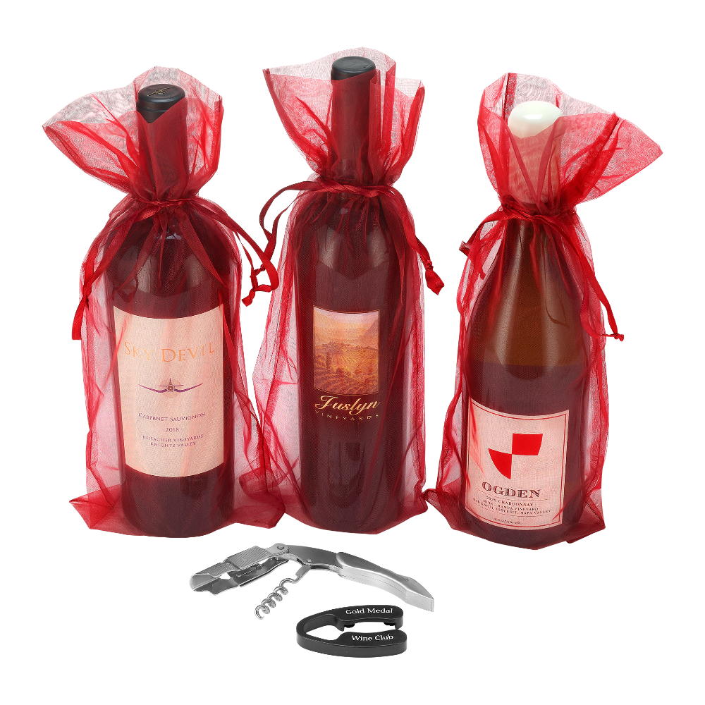 Three bottles of wine in red sheer gift bags next to wine tools